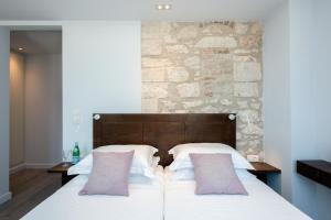 a bedroom with a bed with white sheets and pink pillows at Villa Aelia in Kassiopi