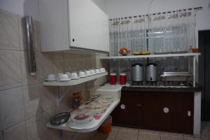 a kitchen with a counter and shelves with dishes at Pousada Orquidário in Santos