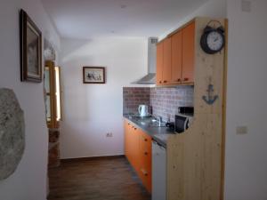 a kitchen with wooden cabinets and a clock on the wall at Apartments Blue & Green in Mošćenička Draga +121 photos