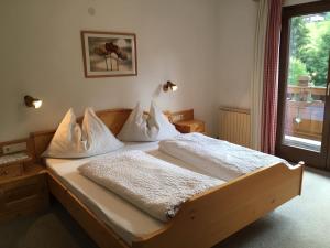 1 dormitorio con cama de madera con sábanas blancas y ventana en Ferienwohnungen Vierthaler en Filzmoos