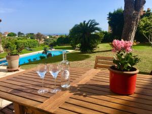 una mesa de madera con copas de vino y una botella en Villa Antoline, en Cagnes-sur-Mer
