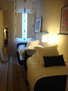 a hotel room with three beds and a window at L'Appart 6 in Aix-en-Provence
