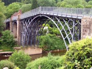 un pont sur une rivière avec un train sur elle dans l'établissement Kings Lodge, à Telford