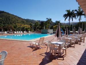 Una fila de mesas y sillas con sombrillas junto a una piscina. en Hotel Cavalinho Branco - Aptos 241 e 317, en Águas de Lindóia