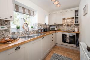 une cuisine avec des armoires blanches et un évier dans l'établissement Lizzies Cottage, à Berwick-upon-Tweed