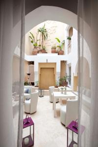a living room with white furniture and potted plants at Riad Dar Maya in Essaouira