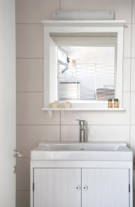 a white bathroom with a sink and a window at Axos Apartments in Hersonissos