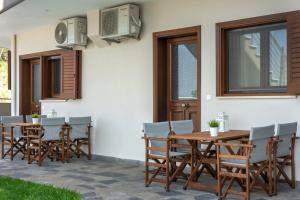 a patio with a wooden table and chairs at Pleiades Casual Living in Nea Roda