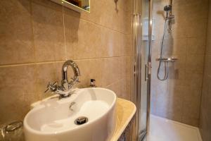 La salle de bains est pourvue d'un lavabo et d'une douche. dans l'établissement Langdon Farm Guest House, à Saundersfoot