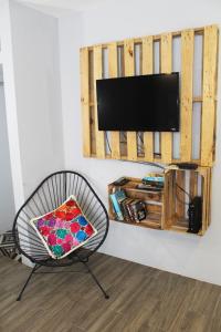 un salon avec une chaise et une télévision murale dans l'établissement Gaia Studios, à Cancún