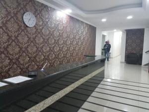 a man walking down an escalator in a building with a clock at Hotel Rio Branco in Sao Paulo