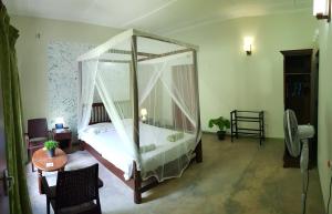 1 dormitorio con cama con dosel y mesa en Lucky Cottage, en Galle