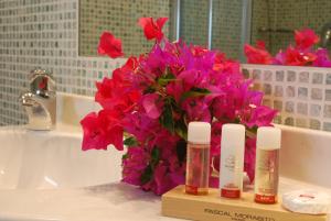 a bathroom sink with a vase of pink flowers next to a sink at UNAHOTELS Club Hotel Ancora in Stintino