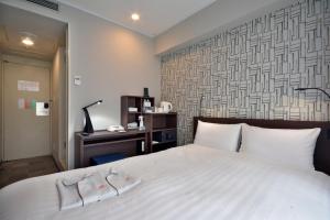 a bedroom with a white bed and a desk at Premier Hotel Cabin Shinjuku in Tokyo