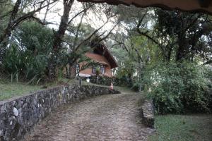 een stenen pad naast een stenen muur en een huis bij Chales Chez Nous in Monte Verde