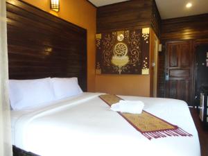 een slaapkamer met een wit bed en een houten hoofdeinde bij Baanfai Guesthouse Chiangkhong in Chiang Khong