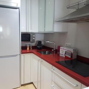 a kitchen with white cabinets and a red counter top at Las Damas Piso18 in Benidorm