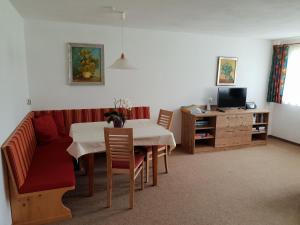 a living room with a table and a red couch at Haus Bilgeri in Nesselwängle