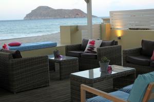 a patio with wicker chairs and tables and the beach at Effi Apartments in Platanias