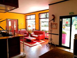 una sala de estar con muebles rojos y paredes amarillas. en Le relais du Haut Limousin, en Eymoutiers