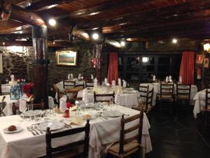 un comedor con mesas y sillas y manteles blancos. en Hotel Can Borrell, en Meranges