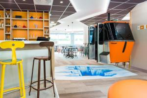 a room with a bar and a tv on the floor at Ibis Styles Sallanches Pays du Mont-Blanc in Sallanches