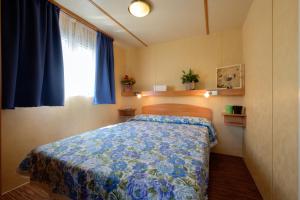 a bedroom with a bed and a window with blue curtains at Ca' Berton Village in Cavallino-Treporti