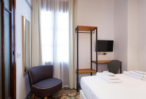 a room with a bed and a chair and a television at Gran H La Marina in Altea
