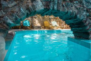 - une piscine dans une grotte avec des chaises bleues dans l'eau dans l'établissement Malaxiana Houses, à Maláxa