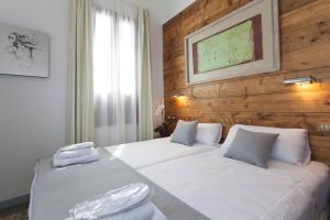 a bedroom with two white beds and a wooden wall at Gran H La Marina in Altea