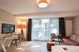 a living room with a couch and a table and a television at Flair Hotel Rieckmann in Bispingen