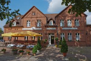 ein großes Backsteingebäude mit Tischen und Sonnenschirmen davor in der Unterkunft Hotel Deutscher Hof in Bad Wilsnack