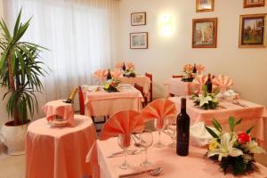 Zimmer mit rosa Tischen, Stühlen und Weinflaschen in der Unterkunft Hotel Colorado in Sottomarina