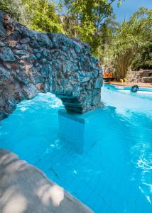 une piscine avec un mur en pierre et de l'eau bleue dans l'établissement Malaxiana Houses, à Maláxa