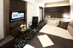 a hotel room with a bed and a flat screen tv at Hotel Bellclassic Tokyo in Tokyo