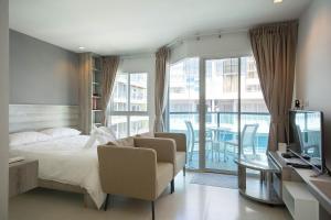 a bedroom with a bed and a tv and a balcony at Grandblue Condominium 504 in Ban Phlong Takhe