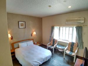 1 dormitorio con 1 cama, 2 sillas y ventana en Fun Chen Resort Hotel, en Liugui