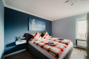 Schlafzimmer mit blauen Wänden und einem Bett mit einer karierten Decke in der Unterkunft Hexe II in Braunlage