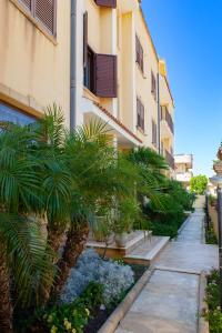 a building with palm trees next to a sidewalk at Sammartano Hotels in Petrosino