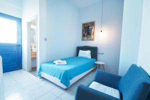 a blue bedroom with a bed and a chair at Aggelos Hotel in Agios Andreas