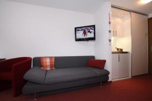 a living room with a couch and a tv on the wall at Hotel Garni Tirol in Walchsee