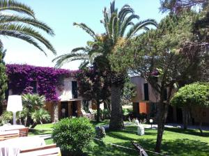 a villa with palm trees and purple ivy at UNAHOTELS Club Hotel Ancora in Stintino