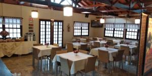 un restaurante con mesas y sillas blancas y ventanas en Pissoloto Hotel en Sertanópolis
