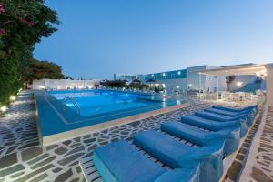 a pool with blue lounge chairs next to a building at Narges Hotel in Aliki