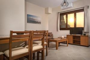 a living room with chairs and a table and a tv at Pleiades Casual Living in Nea Roda