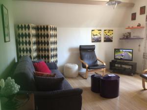 ein Wohnzimmer mit einem Sofa, einem Stuhl und einem TV in der Unterkunft Villa Castelet in Dinard