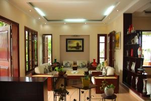 a living room with a couch and tables and windows at Hạ Long Lily Homestay in Ha Long