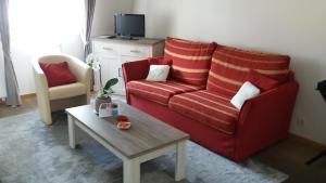 Sala de estar con sofá rojo y mesa de centro en B&B Villa Des Raisins, en Brujas
