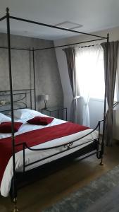 a bedroom with a canopy bed with red and white sheets at B&B Villa Des Raisins in Bruges