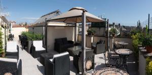 d'une terrasse avec un parasol, des chaises et des tables. dans l'établissement Hotel Anfiteatro Flavio, à Rome